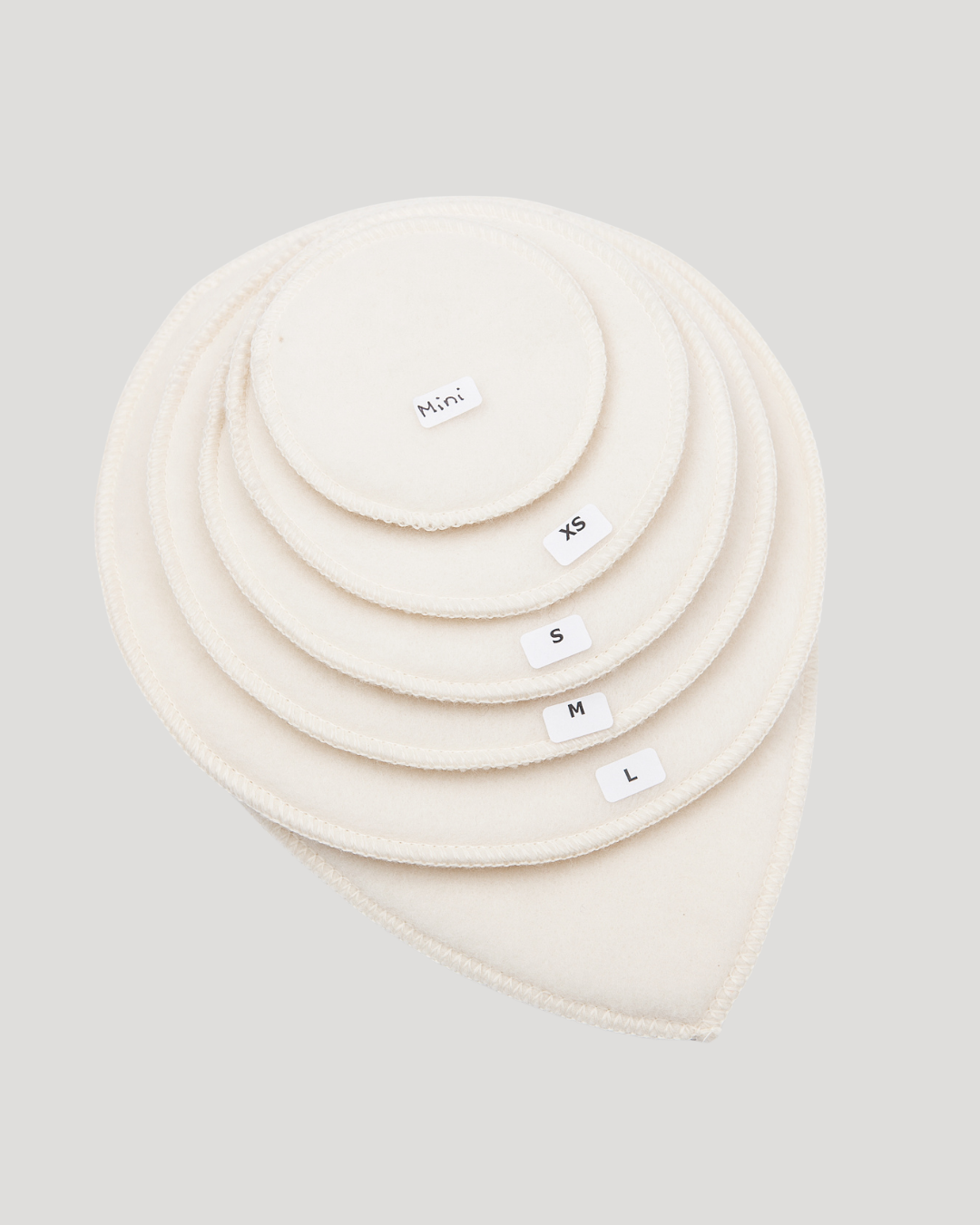 Set of cream-colored circular products with size labels on a light gray background