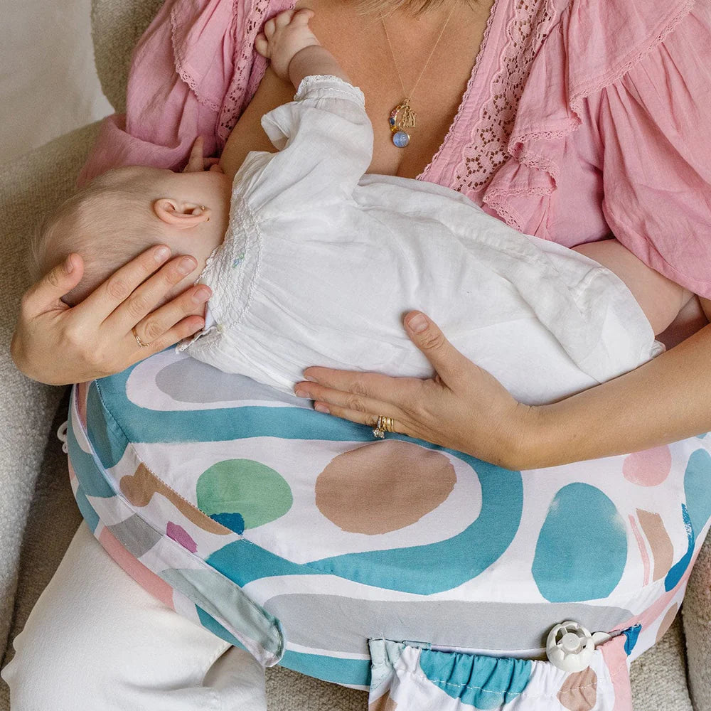 Woman holding a baby on a colorful baby carrier