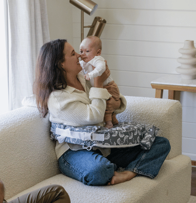 Woman holding a baby on a cushioned chair in a home setting