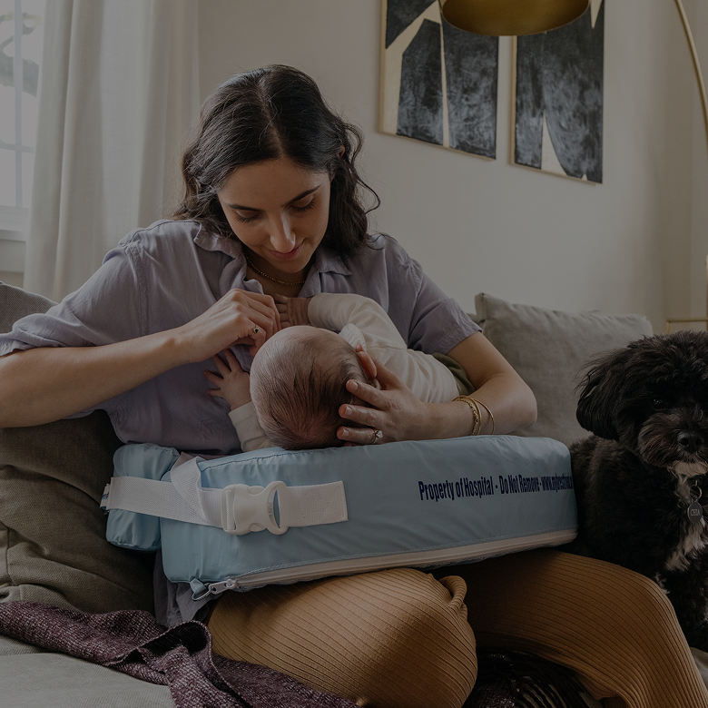 Woman holding a baby on a cushion in a living room with a dog.