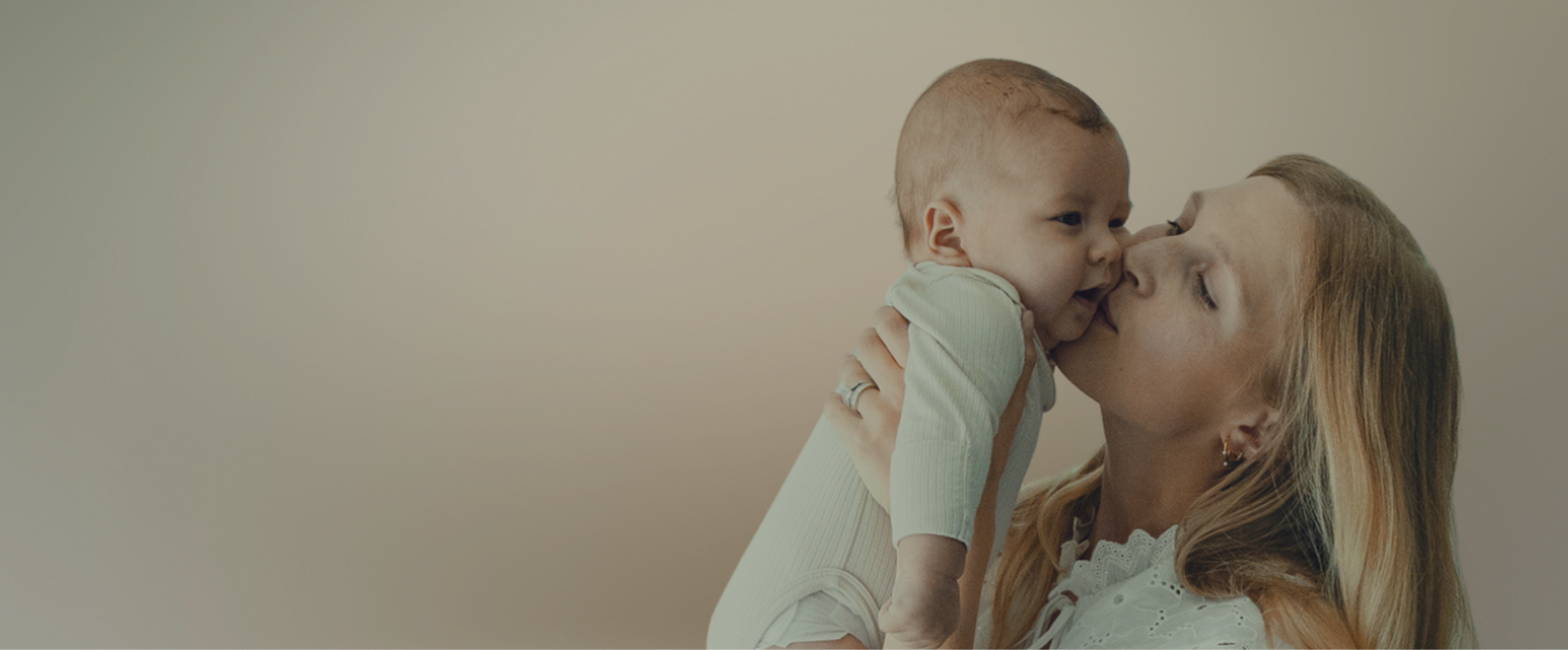 Woman kissing a baby on a plain background