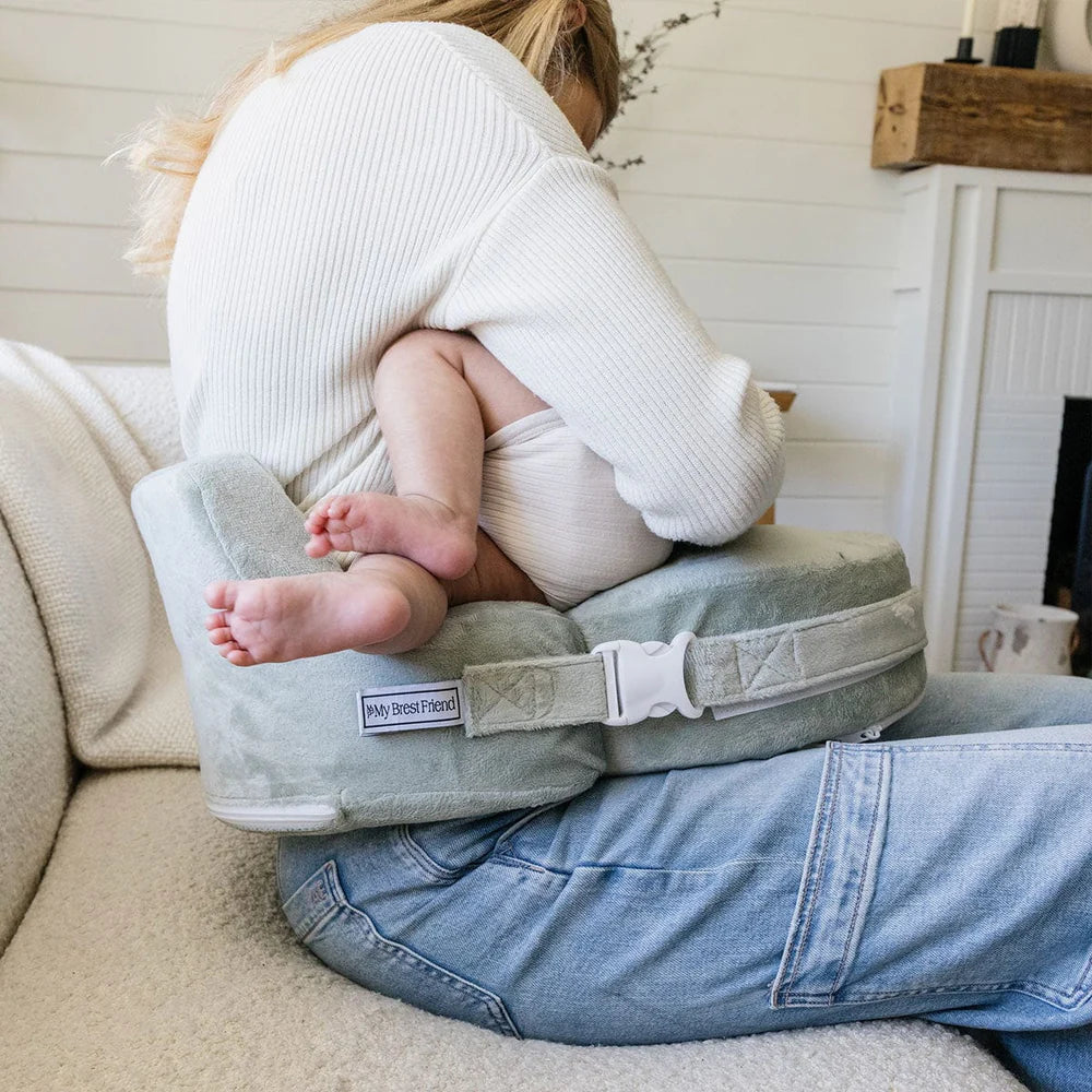 Person holding a baby on a Nursing pillow in a home setting